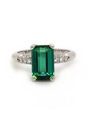 Platinum ring with emerald-cut tourmaline and diamonds on white background