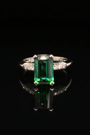 Platinum ring with emerald-cut tourmaline and diamonds on black background
