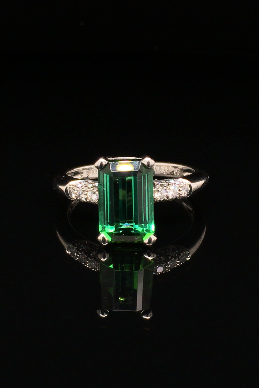 Platinum ring with emerald-cut tourmaline and diamonds on black background