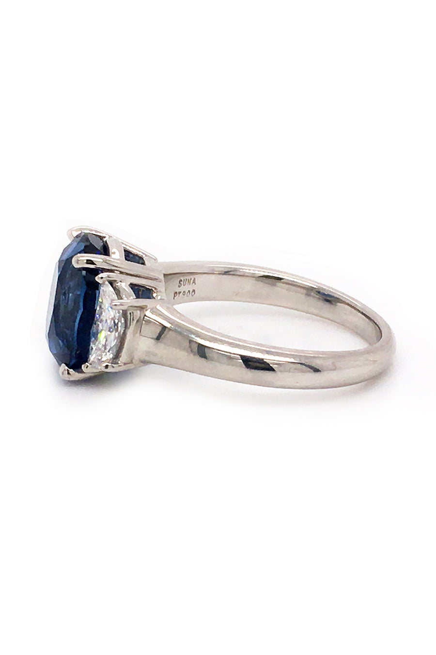 Side view of platinum ring with oval blue sapphire and two half-moon diamonds on white background.
