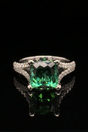 18K white gold ring with a cushion green tourmaline and diamonds on a black background.