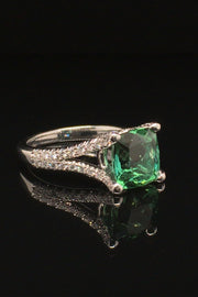 Side view of 18K white gold ring with a cushion green tourmaline and diamonds on a black background.
