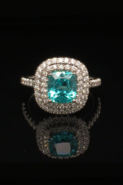Platinum ring with a cushion-cut African paraiba with a double halo of brilliant diamonds on a black background.