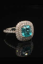 Angle view of platinum ring with a cushion-cut African paraiba with a double halo of brilliant diamonds on a black background.