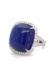 Angle view of 18K white gold ring with a cushion cabochon tanzanite with a diamond halo on a white background