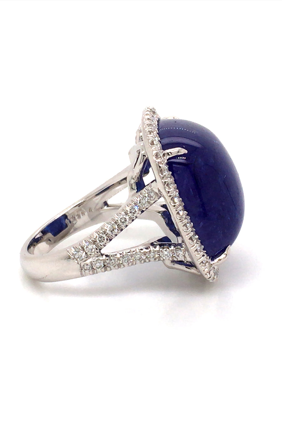 Side view of 18K white gold ring with a cushion cabochon tanzanite with a diamond halo on a white background