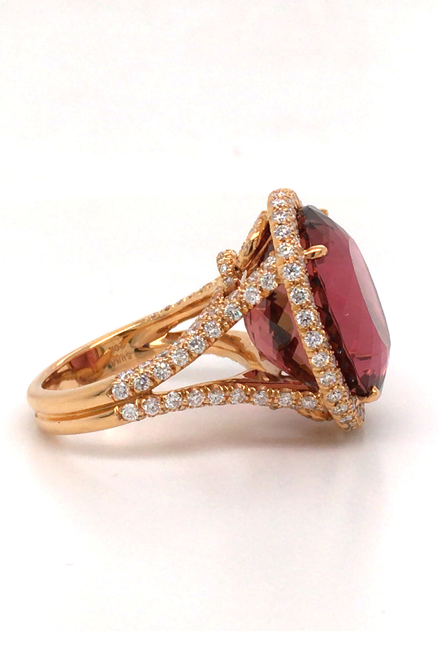 Side view of 20K pink gold ring with large cinnamon tourmaline with diamond halo on a white back background
