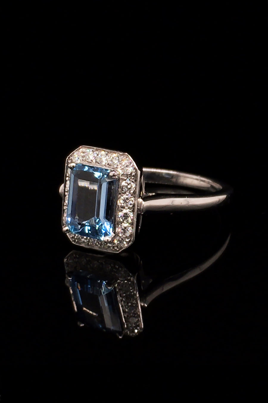 18K white gold ring with an aquamarine and diamonds on black background.