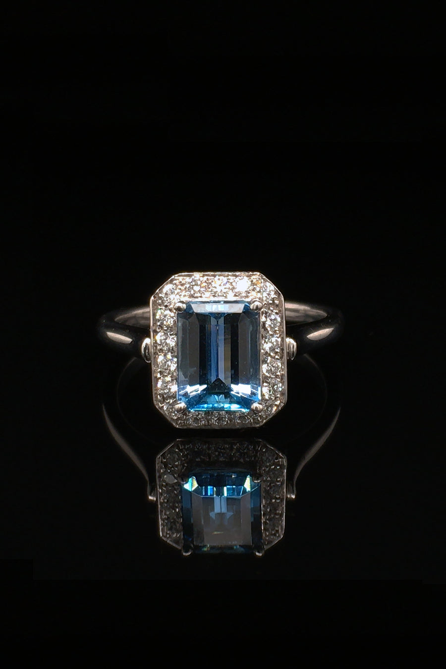 18K white gold ring with an aquamarine and diamonds on black background.