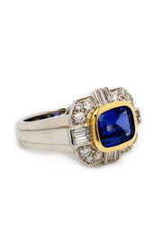 Angle view of ring with a blue sapphire in 18K yellow gold with baguettes and brilliant diamonds set in platinum on a white background