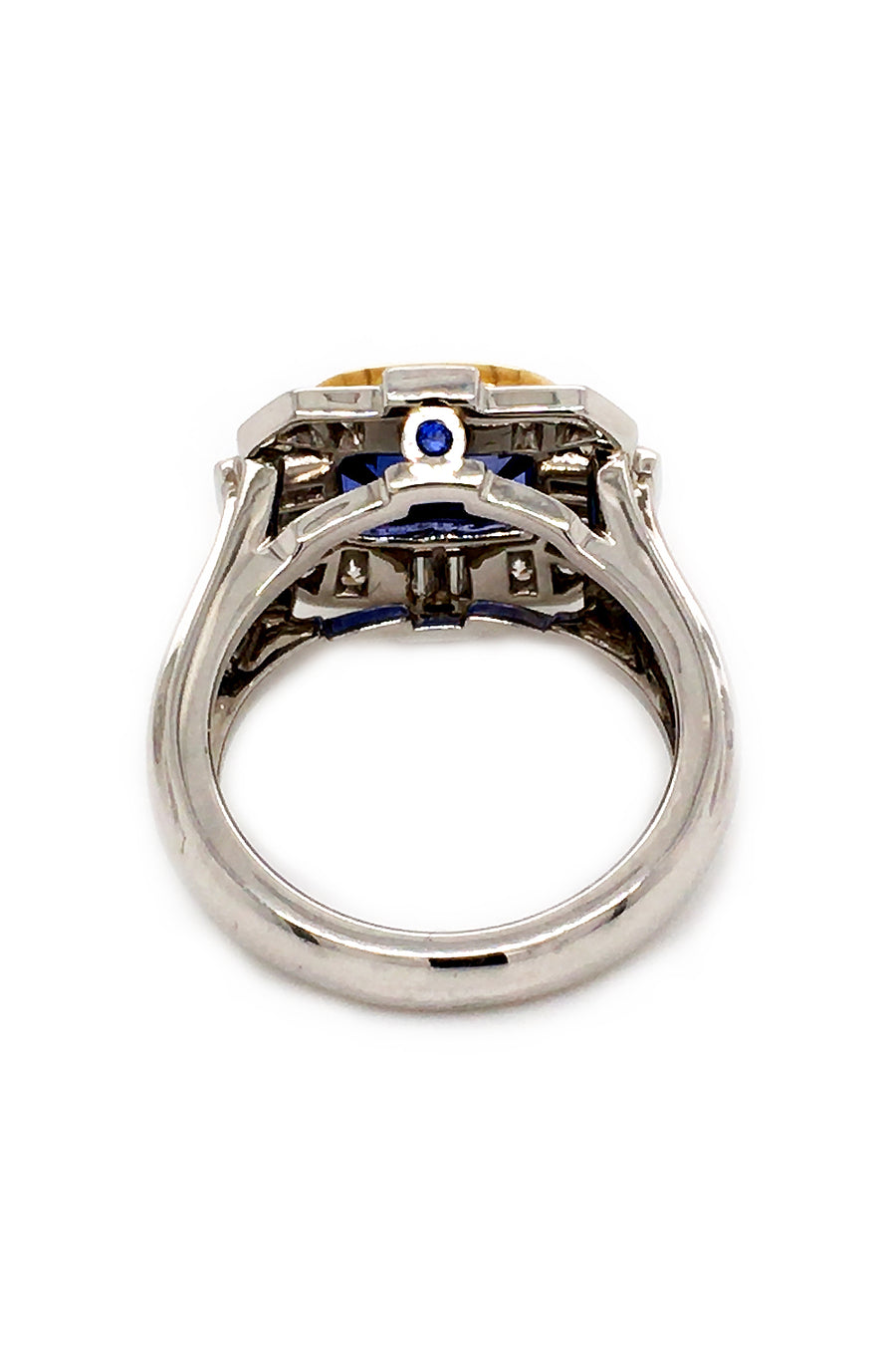 Back view of ring with a blue sapphire in 18K yellow gold with baguettes and brilliant diamonds set in platinum on a white background