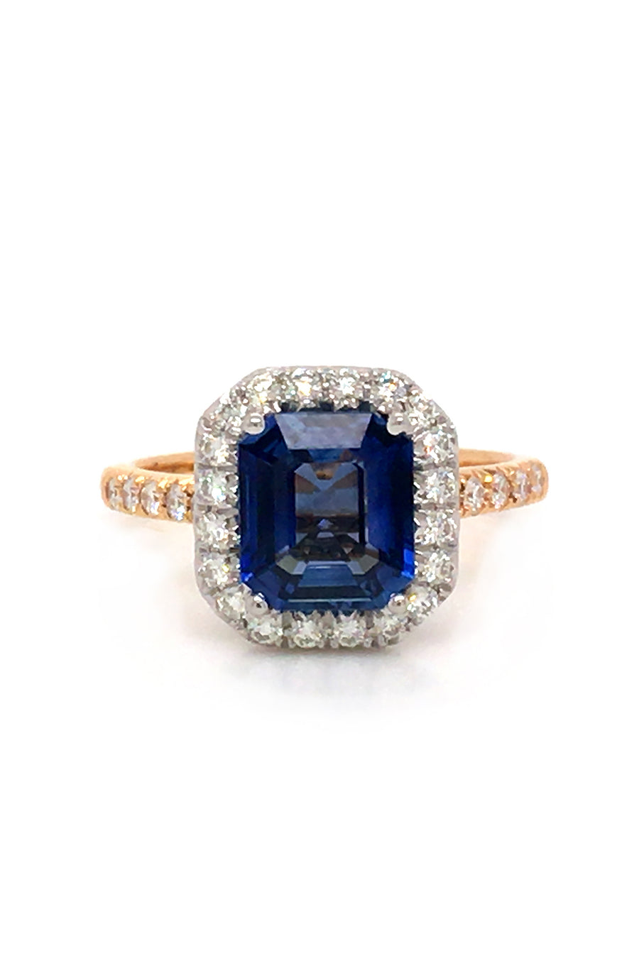 Emerald-cut sapphire set in platinum and surrounded by diamonds with an 18K yellow gold band with diamonds on a white background.