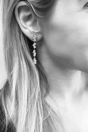 Closeup of woman's ear wearing diamond cluster drop earrings