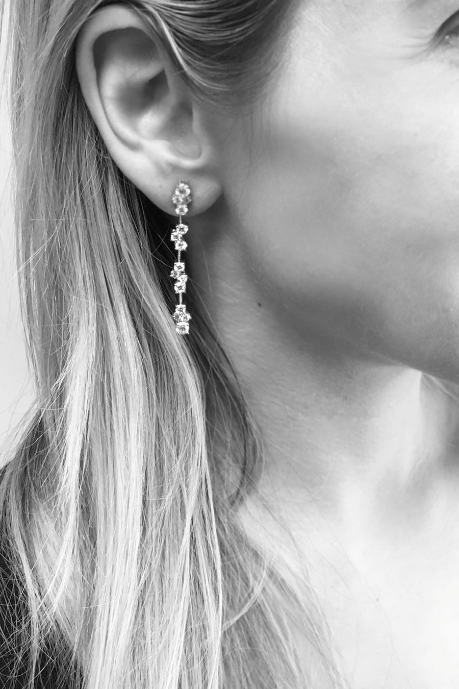 Closeup of woman's ear wearing diamond cluster drop earrings
