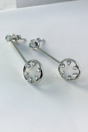 Side view of 18K white gold and diamond drop earrings featuring circle motif on a white background