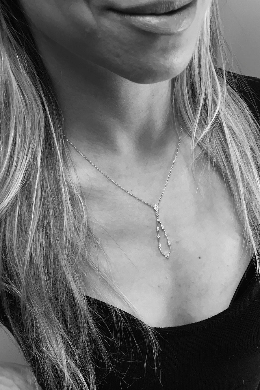 Closeup of woman's neck wearing  teardrop diamond pendant