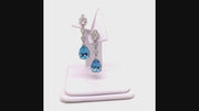Video of rotating platinum drop earrings featuring pear-shaped aquamarines suspended from diamond lace detailing on a white jewelry display
