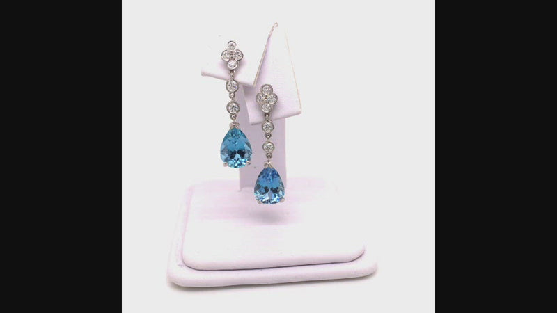 Video of rotating platinum drop earrings featuring pear-shaped aquamarines suspended from diamond lace detailing on a white jewelry display