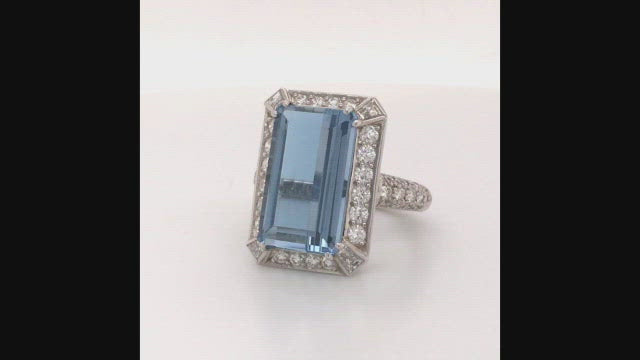 Video of rotating ring with blue gemstone and diamonds on white background
